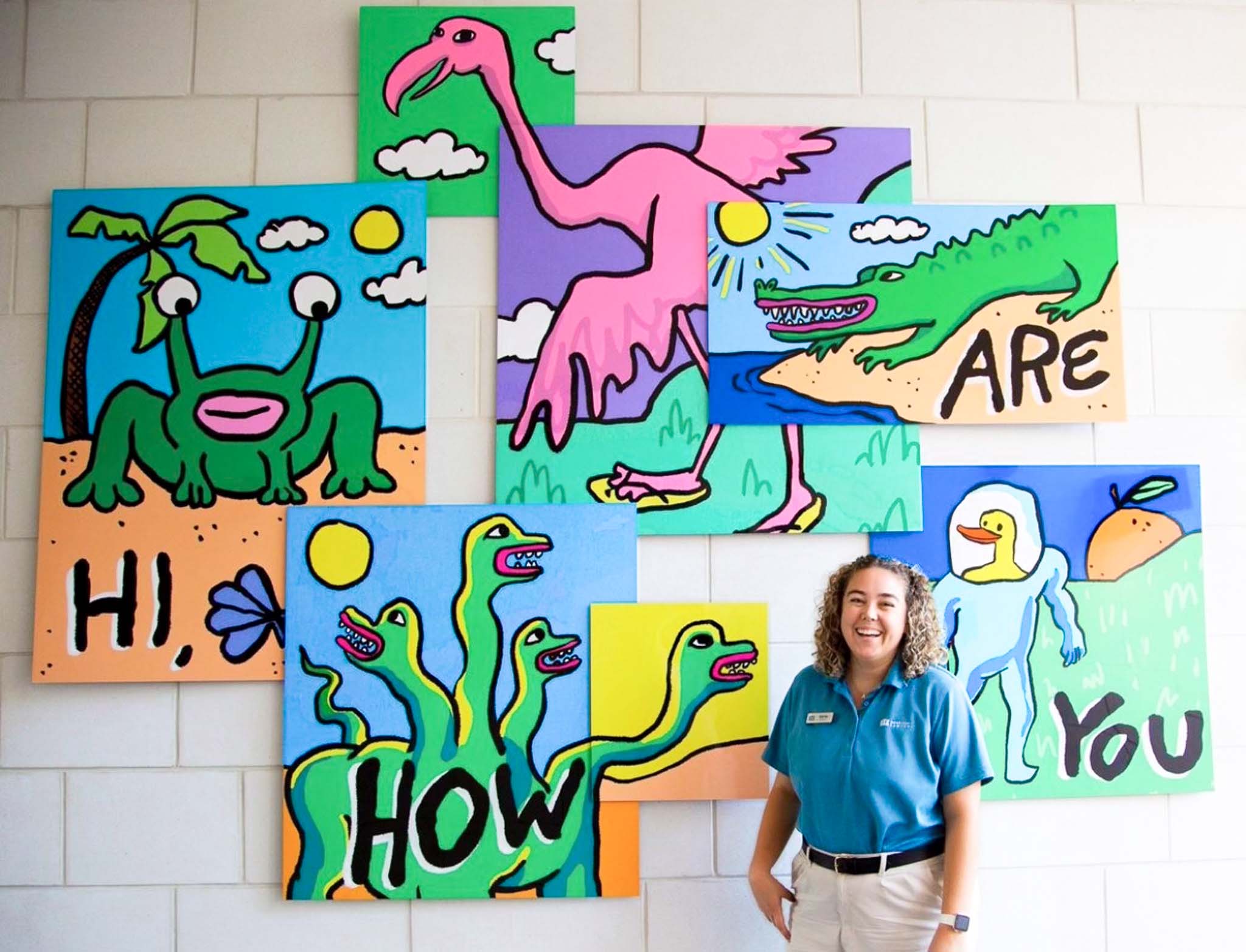 Staff Member in front of Hi, How Are You Mural at Flamingo Crossings Village